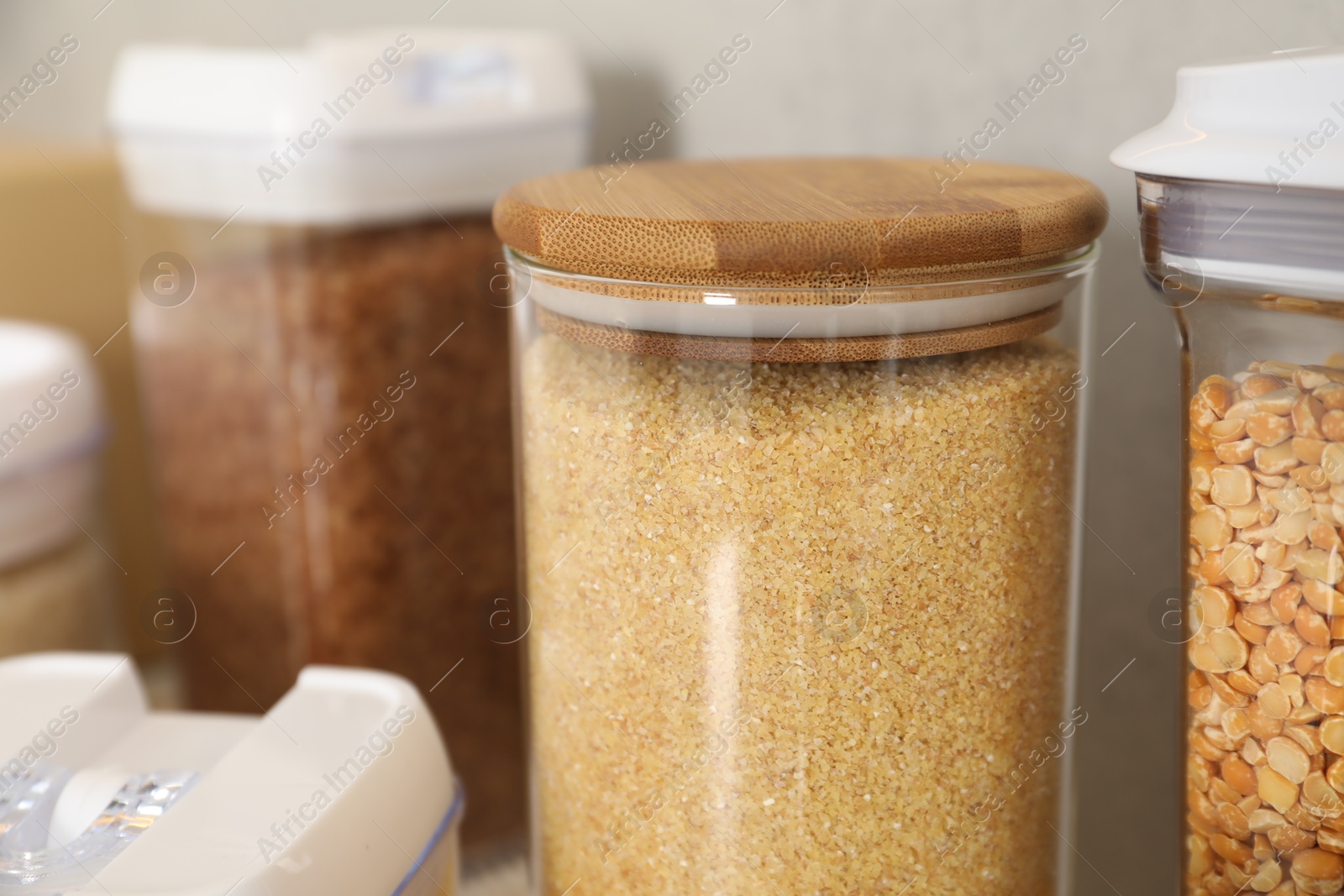 Photo of Different types of cereals in containers on table, closeup