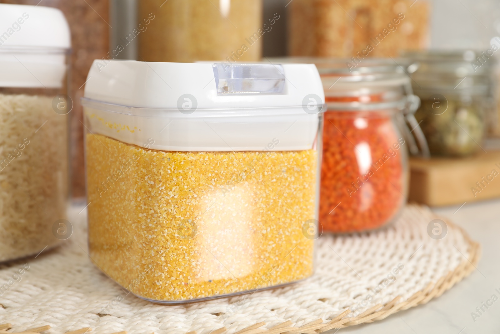 Photo of Different types of cereals and legumes in containers on light table, closeup