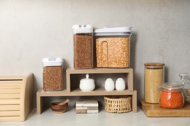 Photo of Different types of cereals and legumes in containers on light marble table