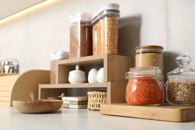 Different types of cereals and legumes in containers on light marble table