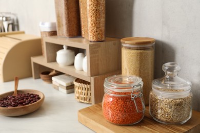 Photo of Different types of cereals and legumes in containers on light marble table