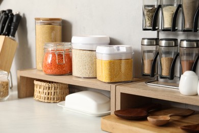 Photo of Different types of cereals and legumes in containers on light marble table