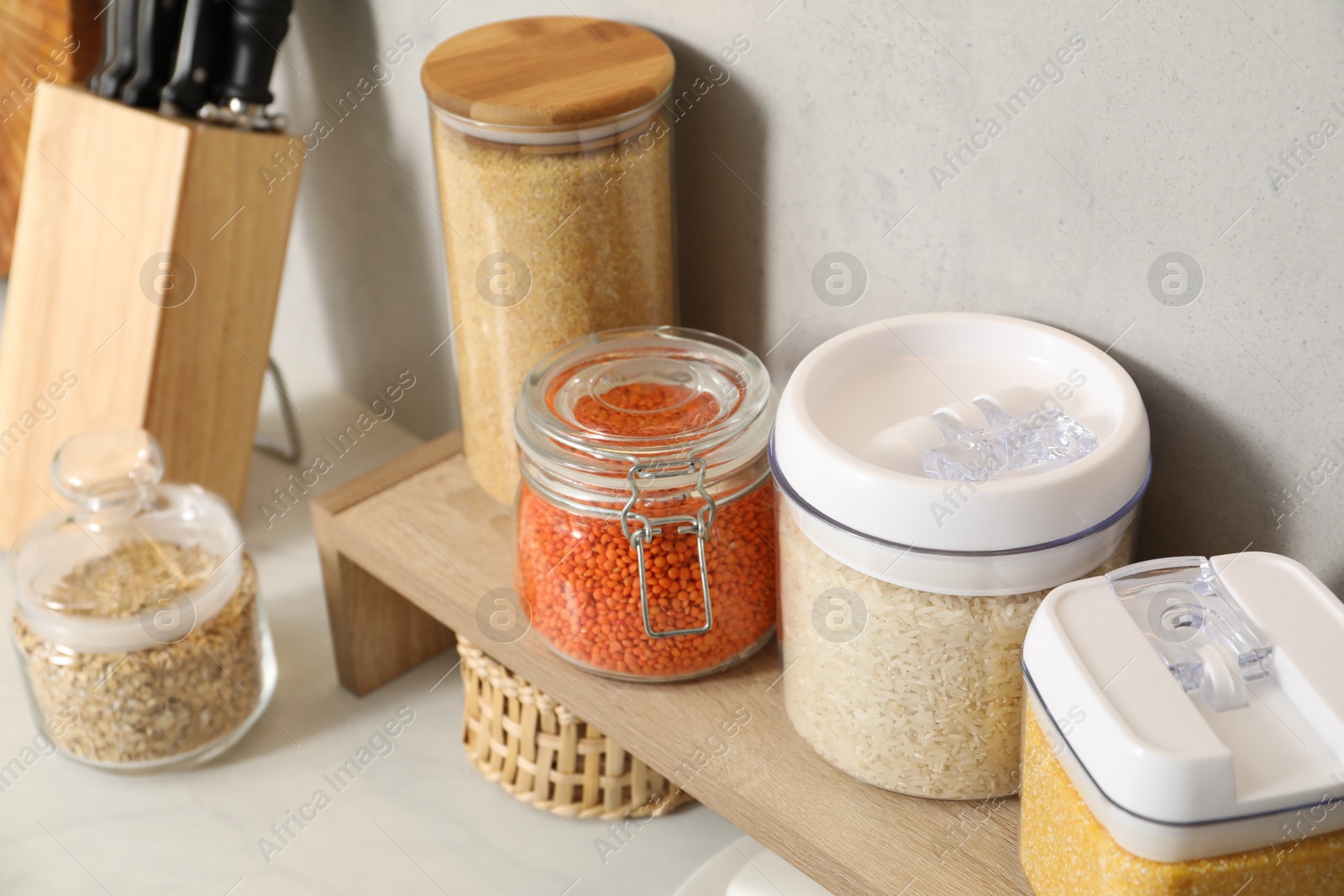 Photo of Different types of cereals and legumes in containers on light table