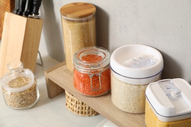 Photo of Different types of cereals and legumes in containers on light table