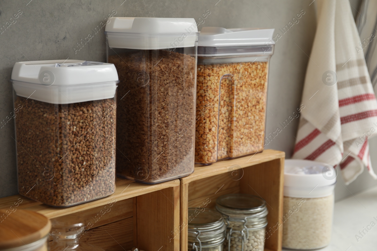 Photo of Different types of cereals and legumes in containers on light table