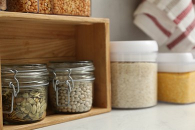 Photo of Different types of cereals, seeds and legumes in containers on light table, closeup