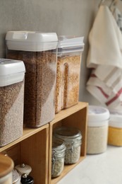 Photo of Different types of cereals and legumes in containers on light table, closeup