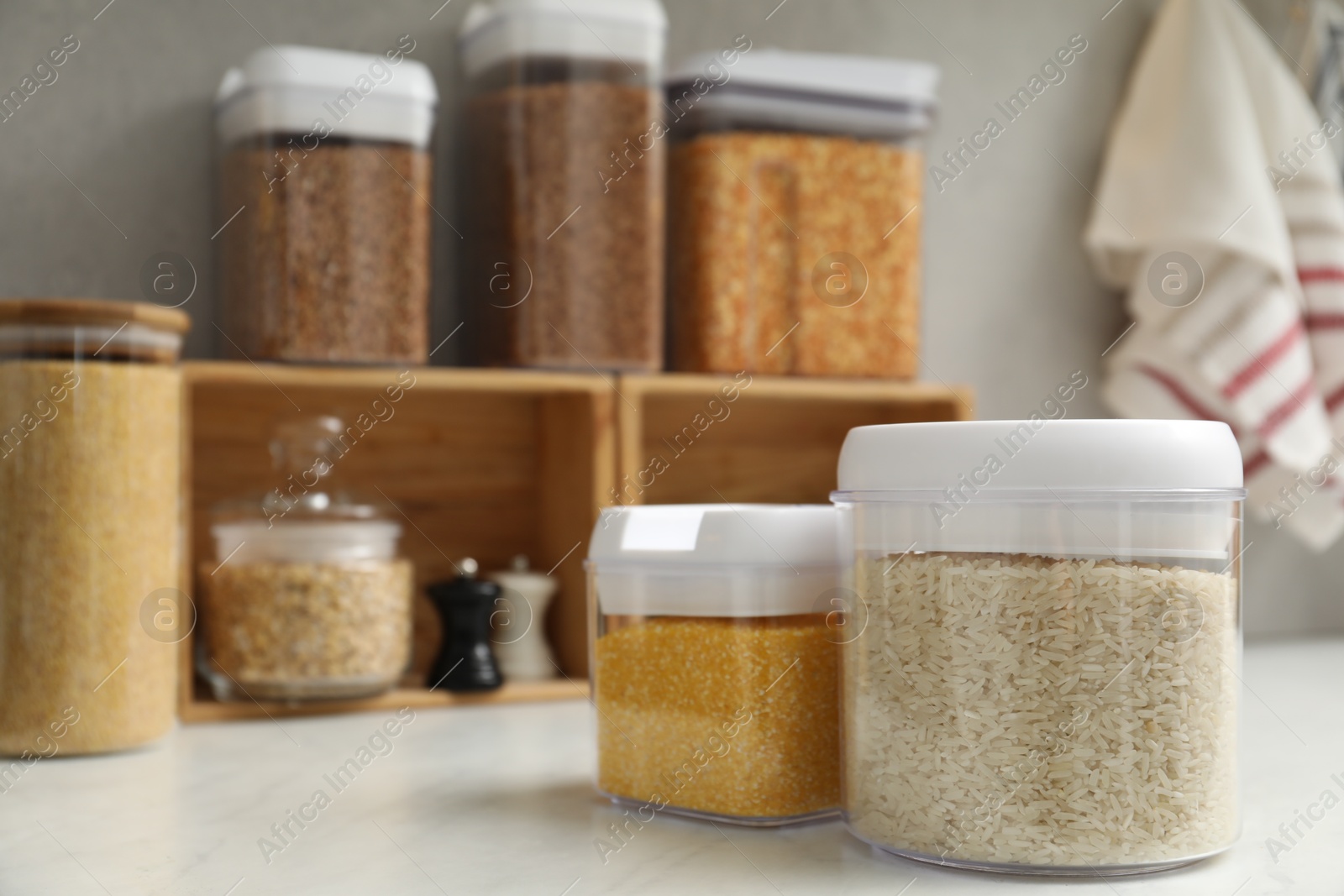 Photo of Different cereals in containers on light marble table, space for text