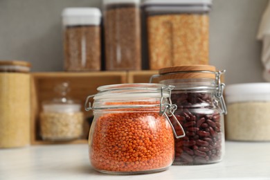 Photo of Different legumes in containers on light table, closeup