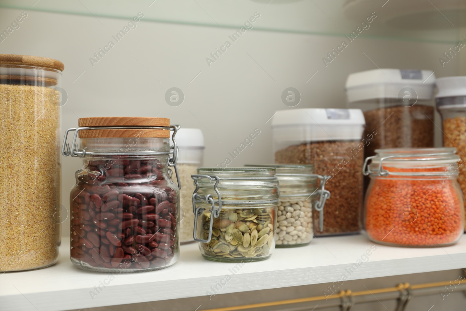 Photo of Different types of cereals, seeds and legumes in containers in closet