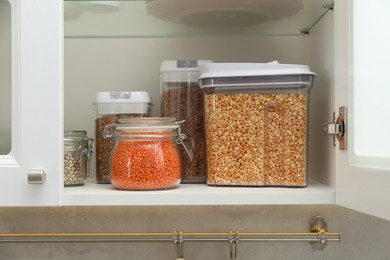 Photo of Different types of cereals and legumes in containers in closet