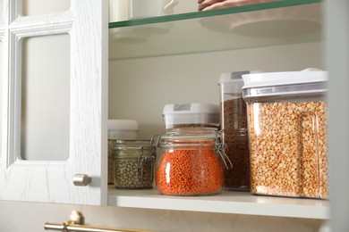 Different types of cereals and legumes in containers in closet