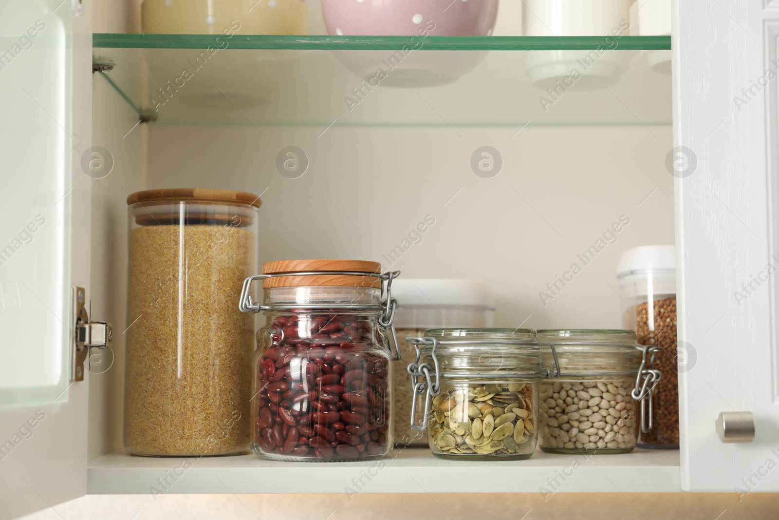 Photo of Different types of cereals, legumes and seeds in containers in closet