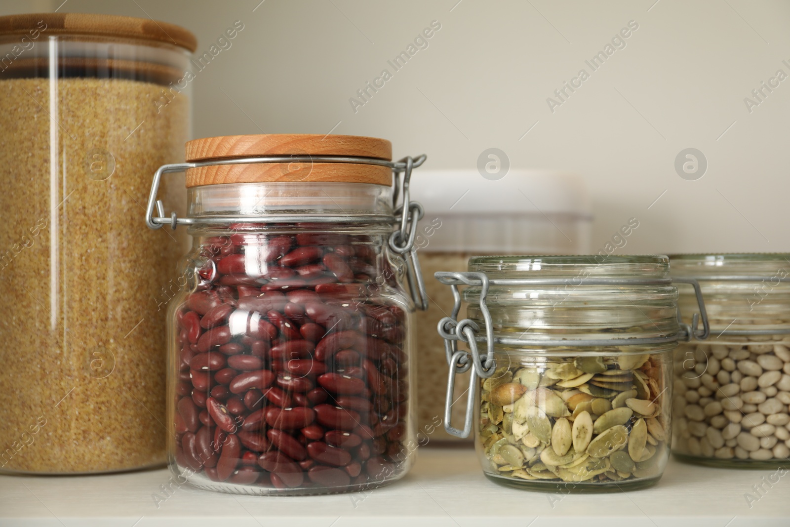 Photo of Different types of cereals, seeds and legumes in containers on white table, closeup