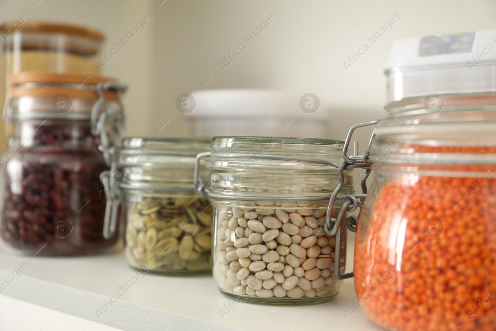 Photo of Different types of cereals, seeds and legumes in containers on white table, closeup