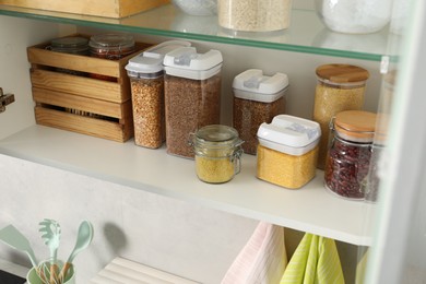 Different types of cereals and legumes in containers in kitchen