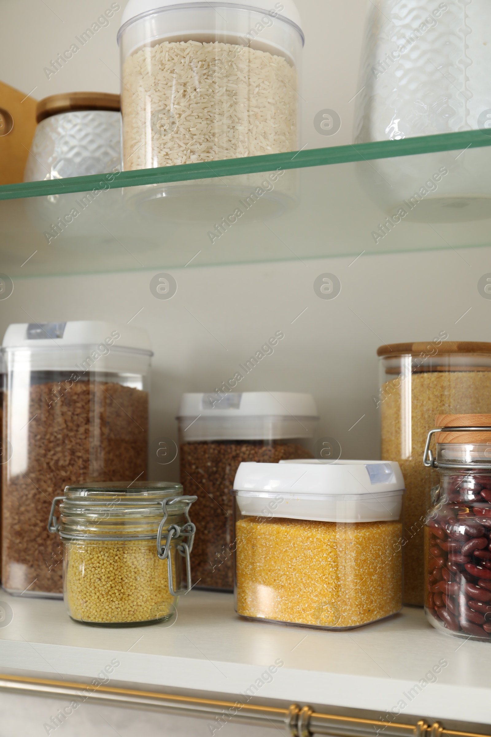 Photo of Different types of cereals and legumes in containers in closet