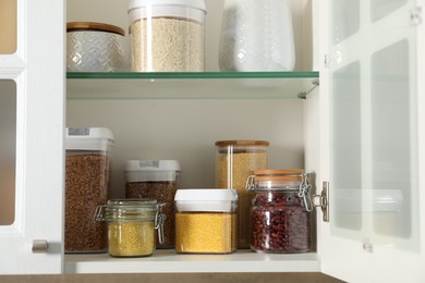 Photo of Different types of cereals and legumes in containers in kitchen