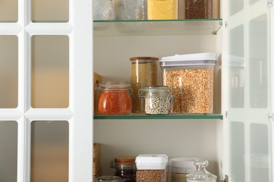 Photo of Different types of cereals and legumes in containers in kitchen