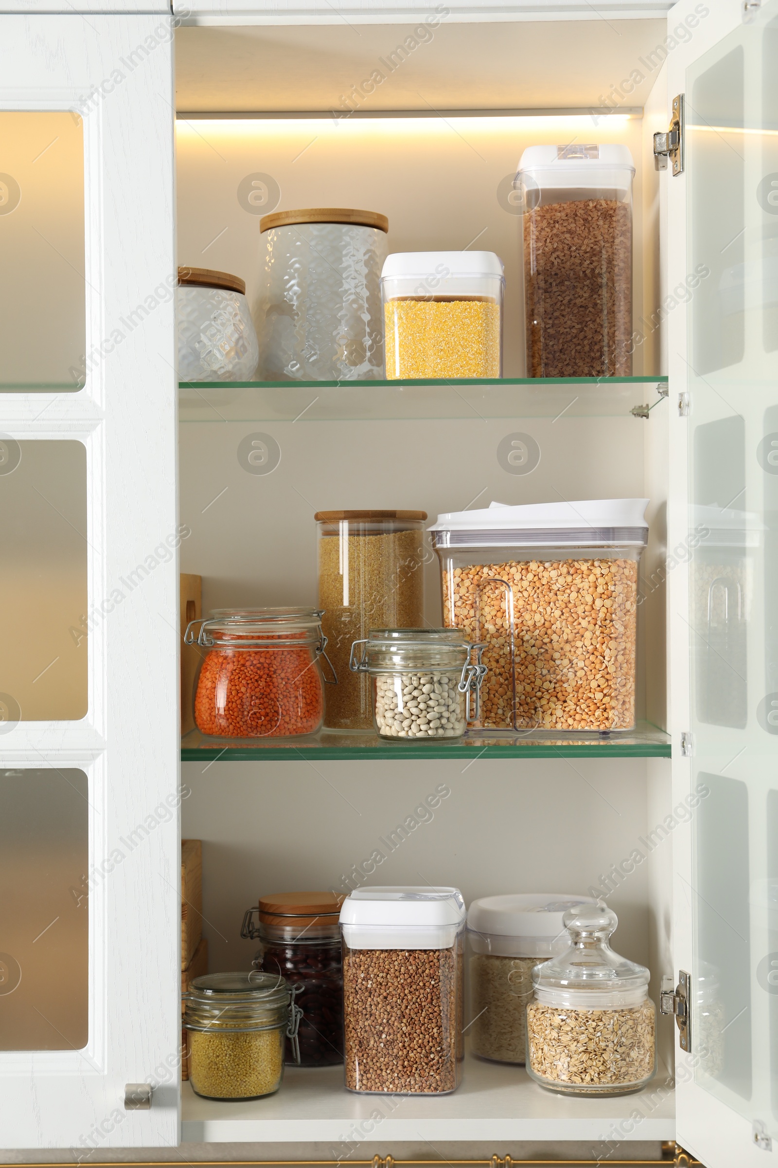 Photo of Different types of cereals and legumes in containers in kitchen