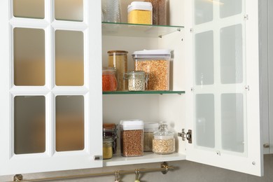 Photo of Different types of cereals and legumes in containers in kitchen