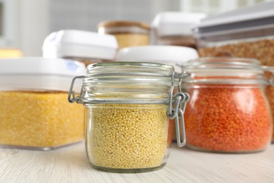 Photo of Different types of cereals and legumes in containers on white wooden table, closeup