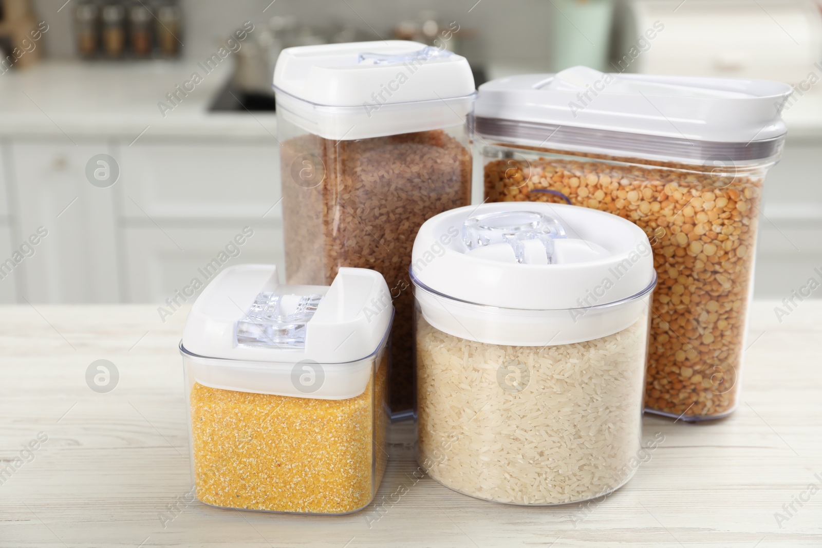 Photo of Different types of cereals and legumes in containers on white wooden table in kitchen