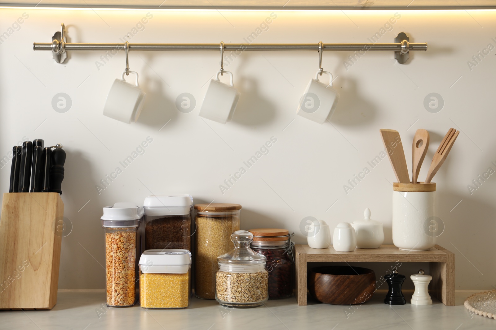 Photo of Different types of cereals and legumes in containers on light marble table in kitchen