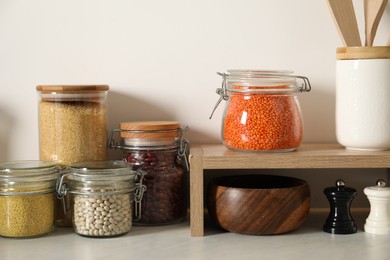 Photo of Different types of cereals and legumes in containers on light marble table in kitchen