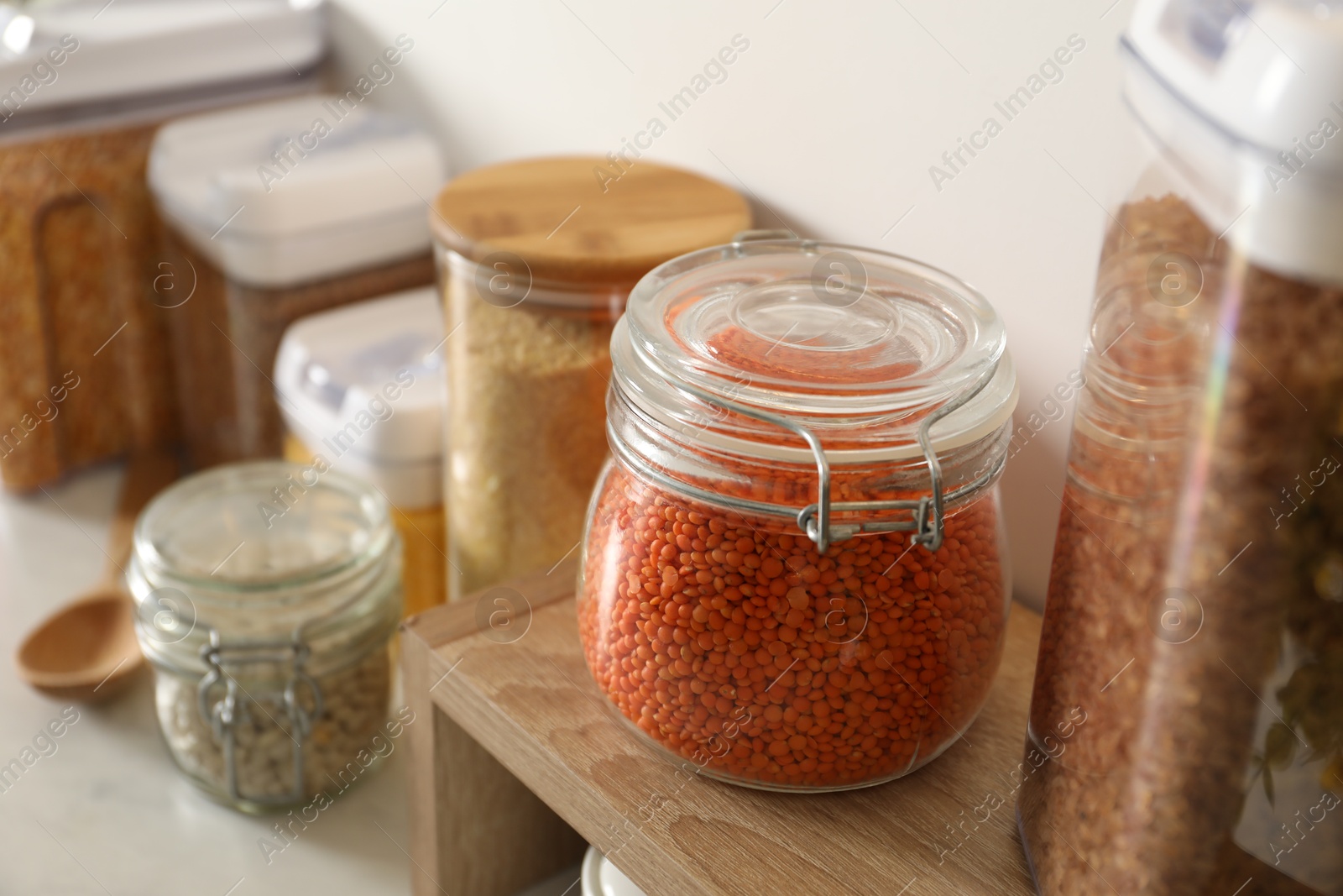 Photo of Different types of cereals and legumes in containers on light table, closeup