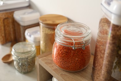 Photo of Different types of cereals and legumes in containers on light table, closeup