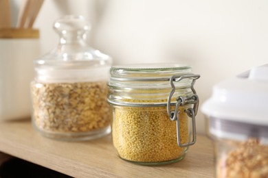 Photo of Different types of cereals in containers on wooden surface, closeup