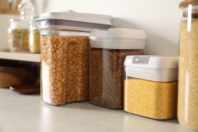 Photo of Different types of cereals and legumes in containers on light marble table, closeup