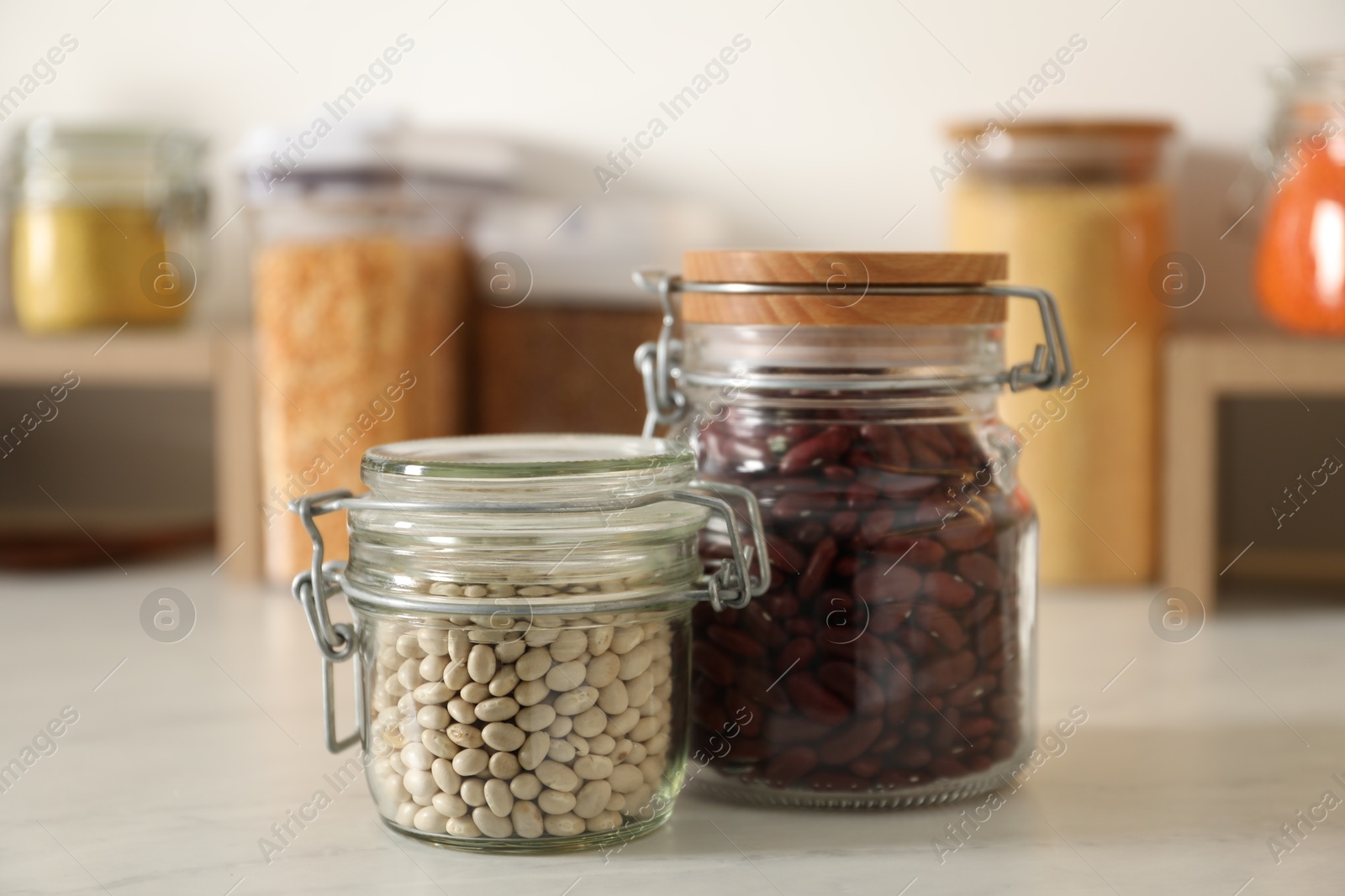 Photo of Different types of legumes in containers on light marble table, closeup