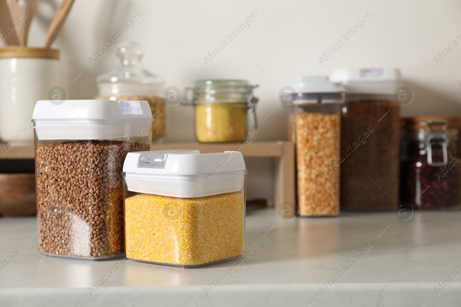 Photo of Different types of cereals in containers on light marble countertop, space for text