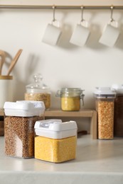 Photo of Different types of cereals in containers on light marble countertop