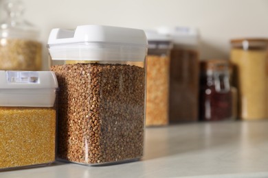 Different types of cereals in containers on light marble table, closeup. Space for text