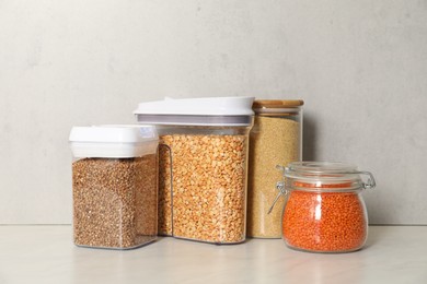 Photo of Different types of cereals and legumes in containers on light marble table