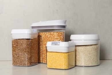 Photo of Different types of cereals in containers on light marble table