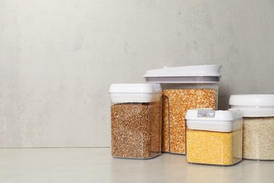 Photo of Different types of cereals in containers on light marble table, space for text