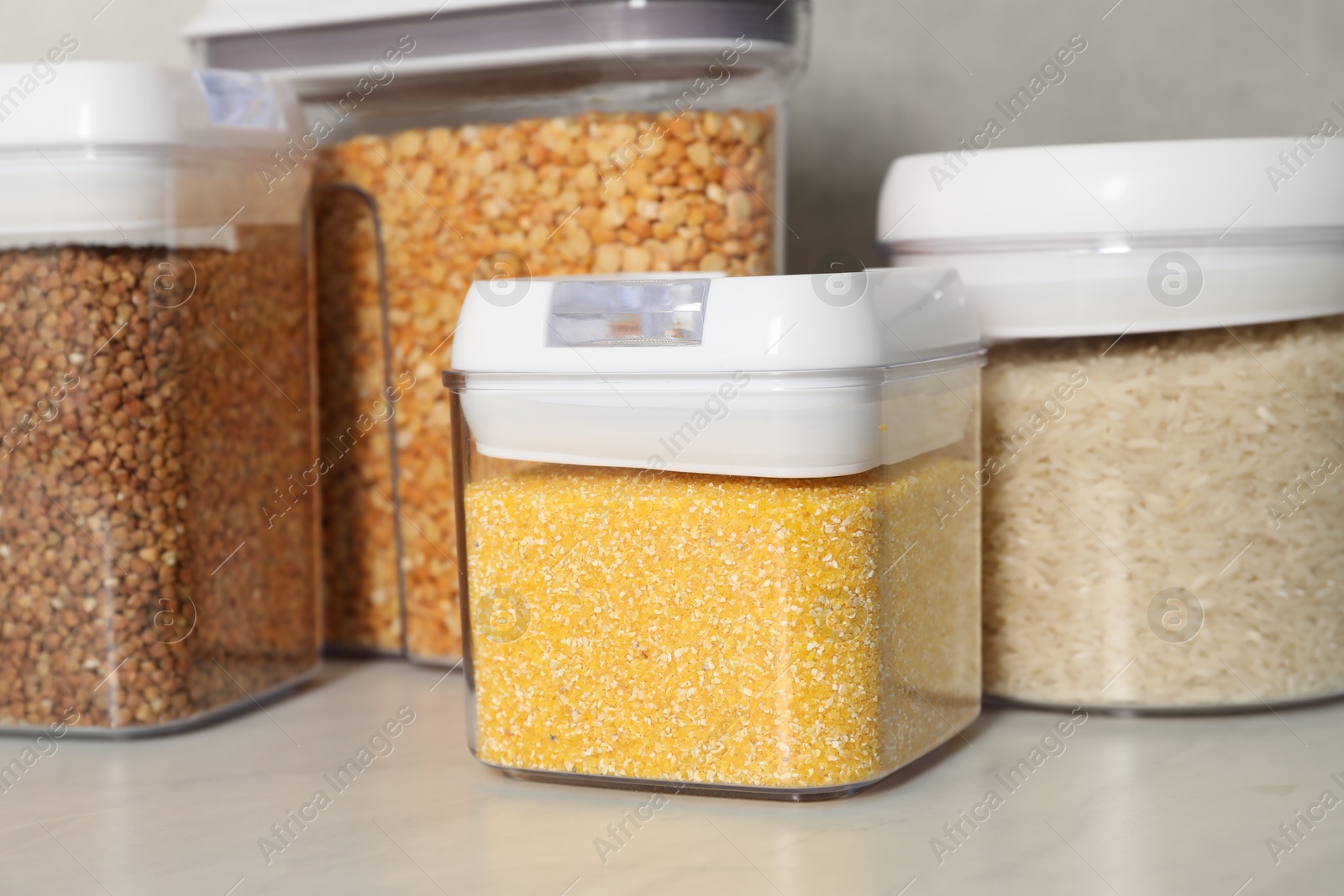 Photo of Different types of cereals in containers on light marble table, closeup