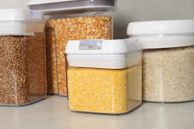 Photo of Different types of cereals in containers on light marble table, closeup