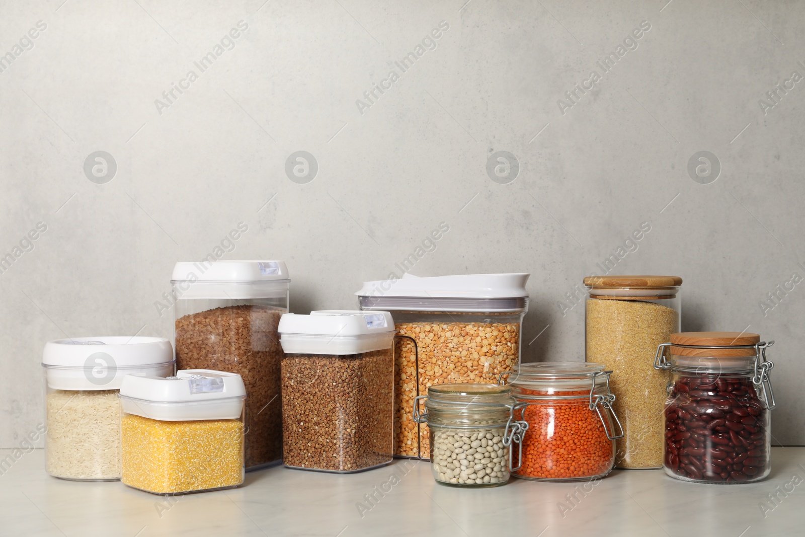 Photo of Different types of cereals and legumes in containers on light marble table