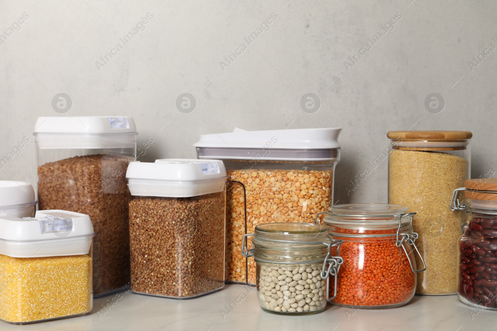 Photo of Different types of cereals and legumes in containers on light marble table