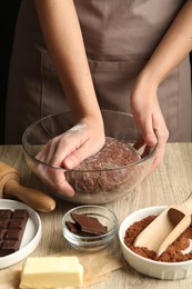 Photo of Woman kneading chocolate dough at wooden table, closeup