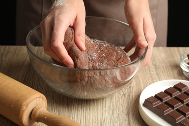 Photo of Woman kneading chocolate dough at wooden table, closeup