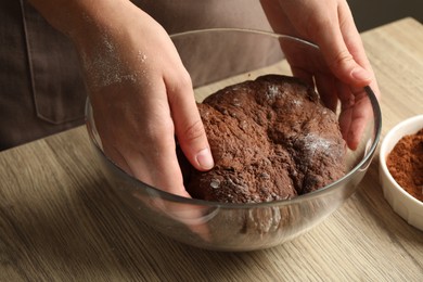 Photo of Woman kneading chocolate dough at wooden table, closeup