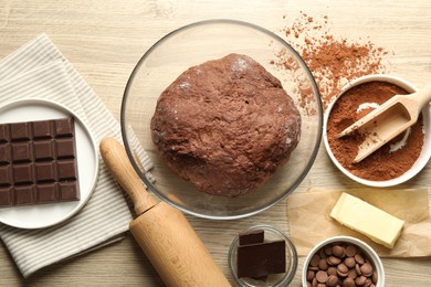 Photo of Chocolate dough and ingredients on wooden table, flat lay