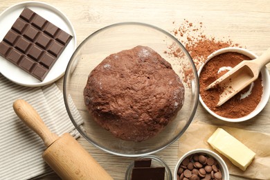 Photo of Chocolate dough and ingredients on wooden table, flat lay