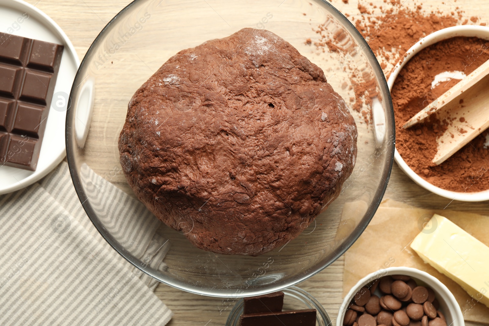 Photo of Chocolate dough and ingredients on wooden table, flat lay